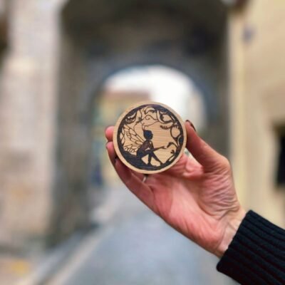 Décapsuleur magnétique en bois pyrogravé motif fée, création artisanale Pyro’Art par Louve de Lune, photographie en extérieur dans une rue ancienne.