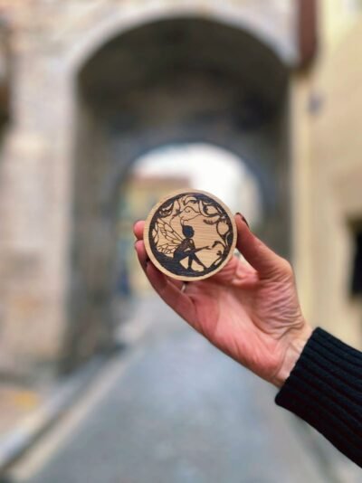Décapsuleur magnétique en bois pyrogravé motif fée, création artisanale Pyro’Art par Louve de Lune, photographie en extérieur dans une rue ancienne.